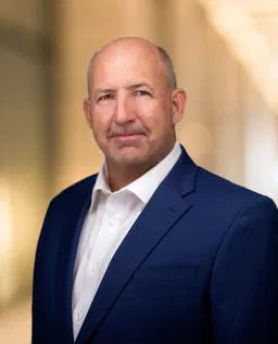 Bald man in formal attire posing for a business headshot.