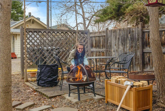 Person tending to a small fire pit in a cozy backyard setting.