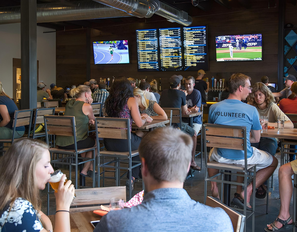 A lively bar scene featuring a group of people engaged in conversation while seated at tables.