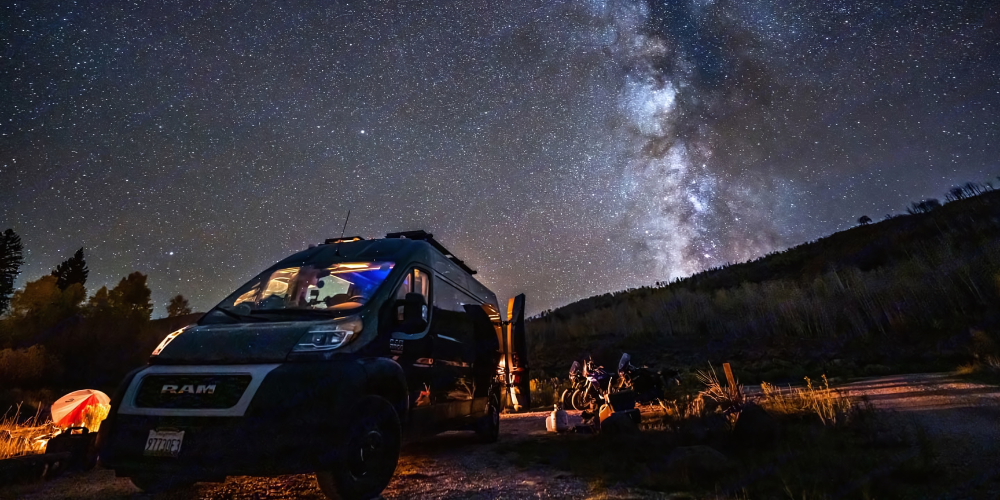 A camper van parked under a starry night sky, providing a cozy and adventurous setting for outdoor enthusiasts