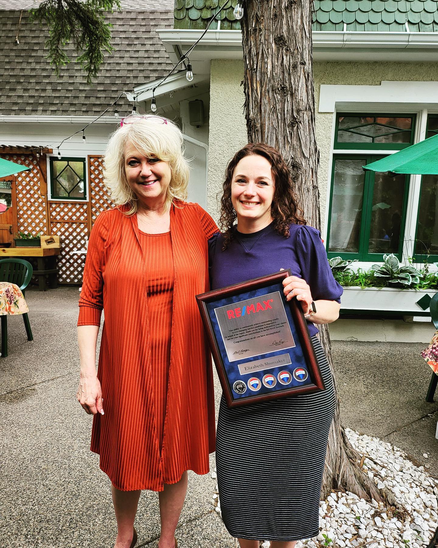 Two women standing side by side, holding a framed award