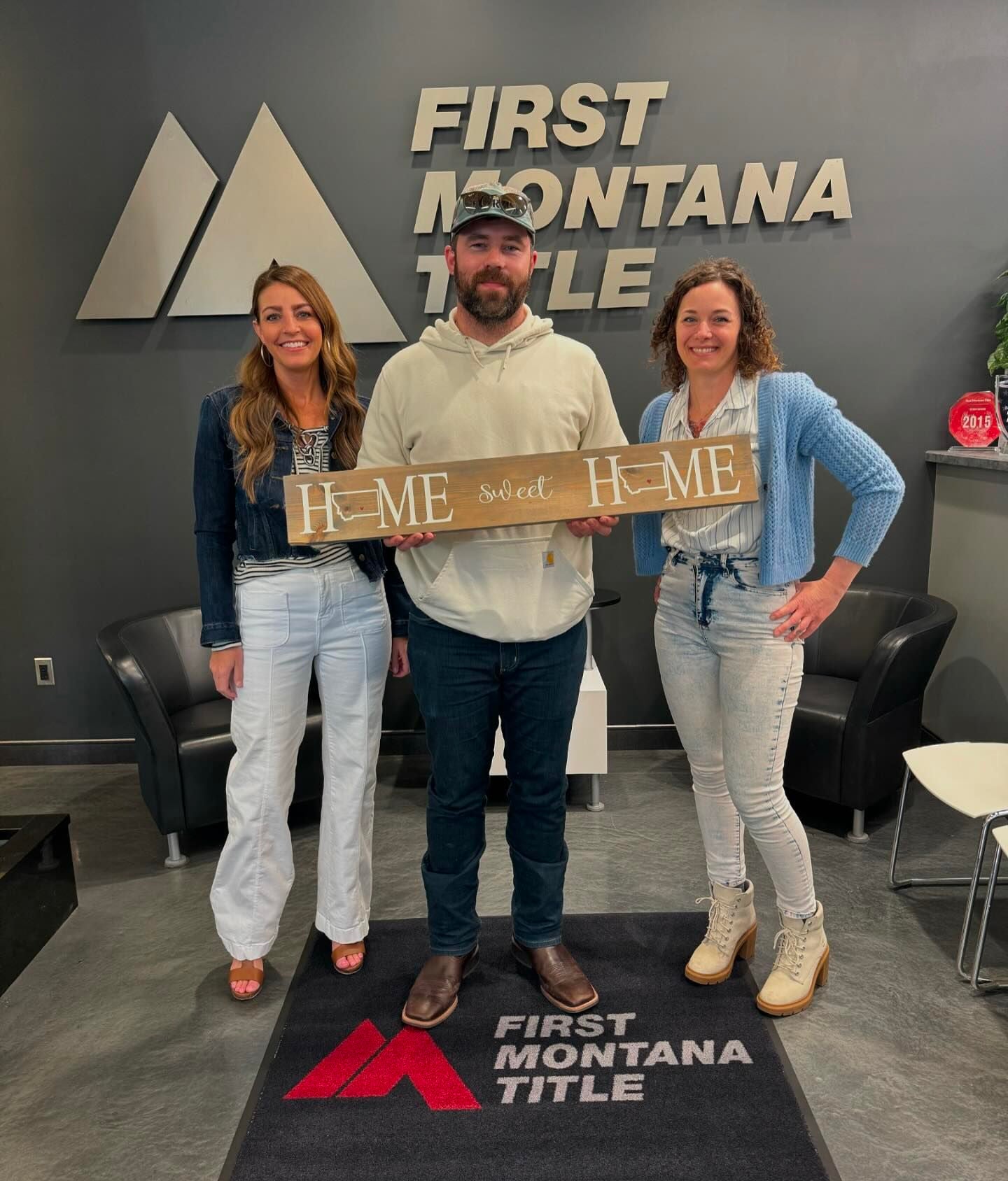 A group of three people standing next to a sign that reads "First Montana Tile