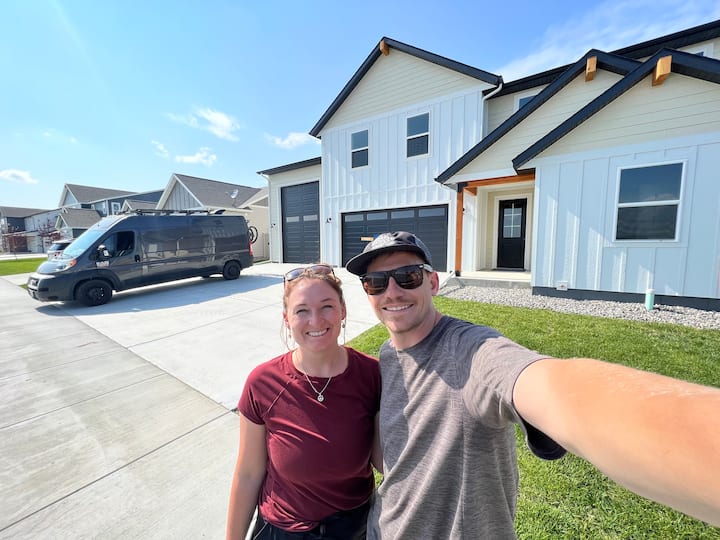 A man and woman posing for a selfie outside their house