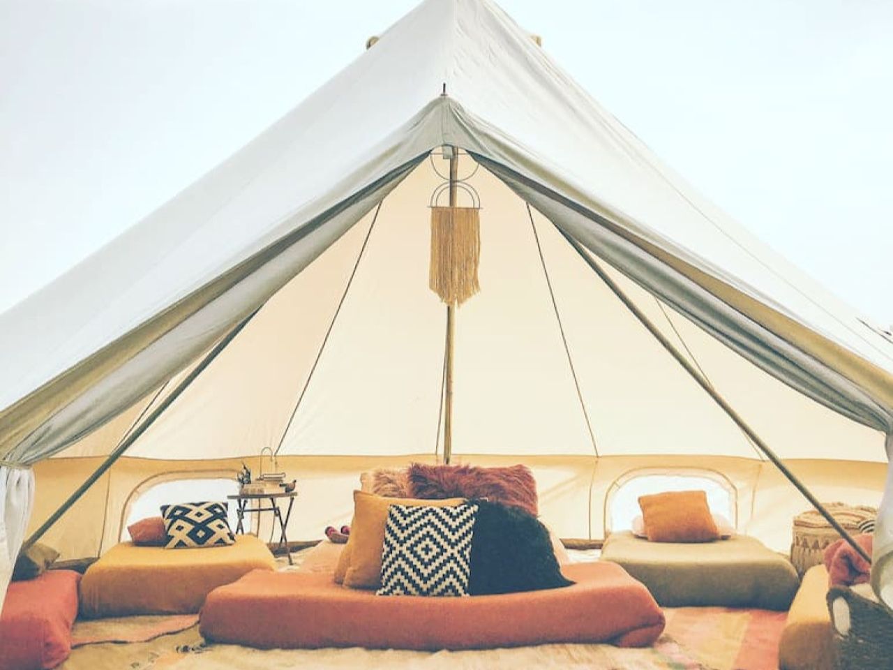 Interior of a cozy tent with colorful cushions and a boho design.