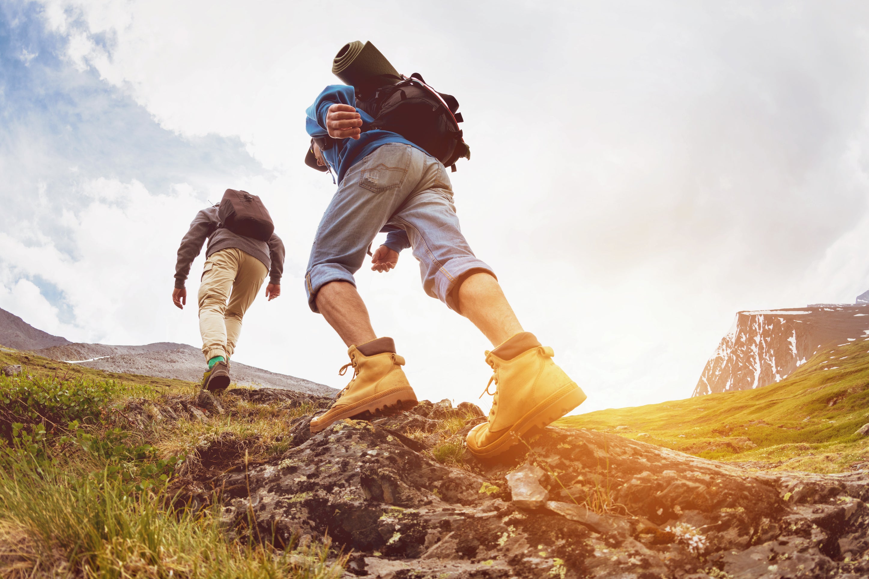 Two people climb a hill with backpacks, immersed in nature and the journey ahead.