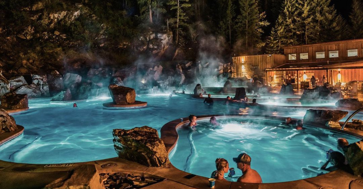  A serene view of the lodge's hot springs illuminated by moonlight, surrounded by lush greenery at night.