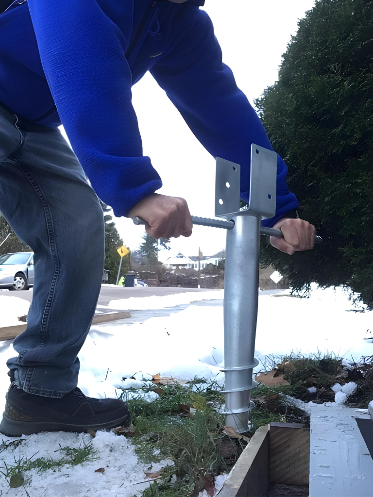 A man supporting a tree with a metal pole to ensure its stability and prevent it from falling.