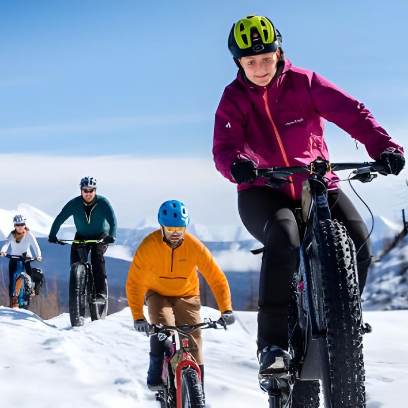 A group of individuals cycling on a snowy slope, showcasing a blend of winter sports and outdoor adventure.