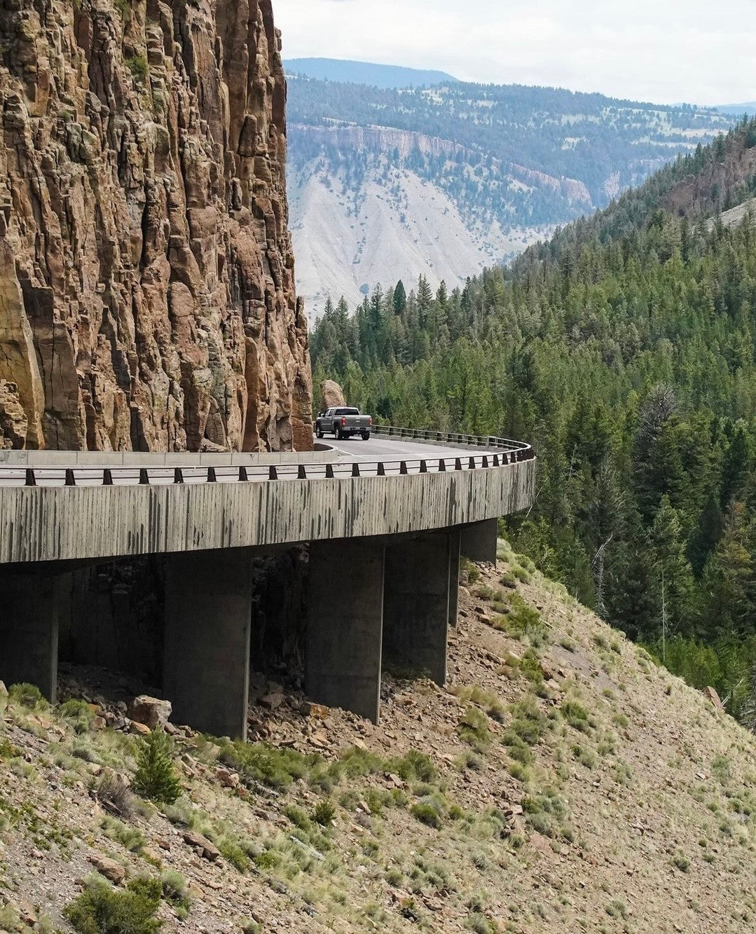  A car travels along a highway, crossing a bridge with a clear sky in the background, showcasing a scenic view.