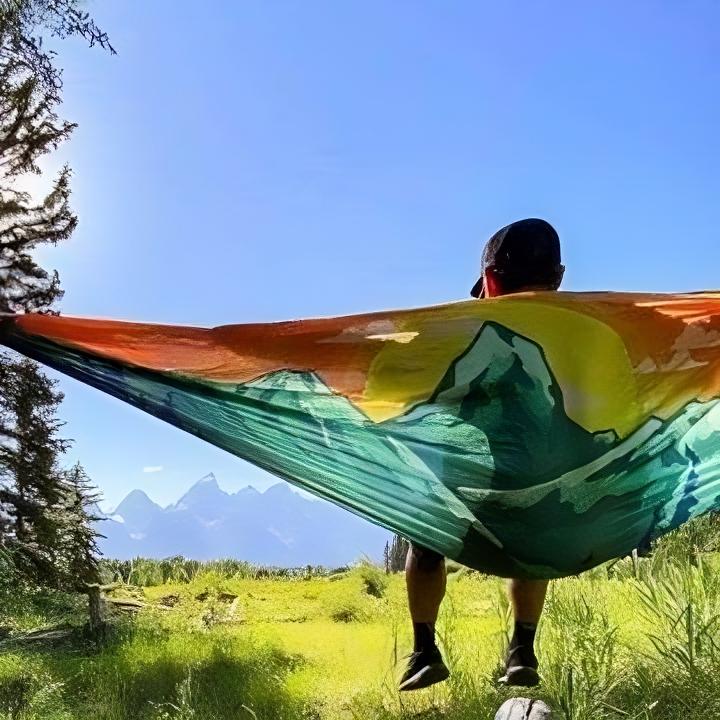 A person relaxing in a hammock with majestic mountains in the background, creating a serene and peaceful scene.