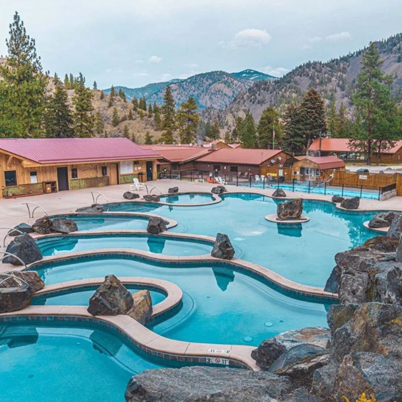 Empty outdoor hot springs with mountain views and surrounding trees.