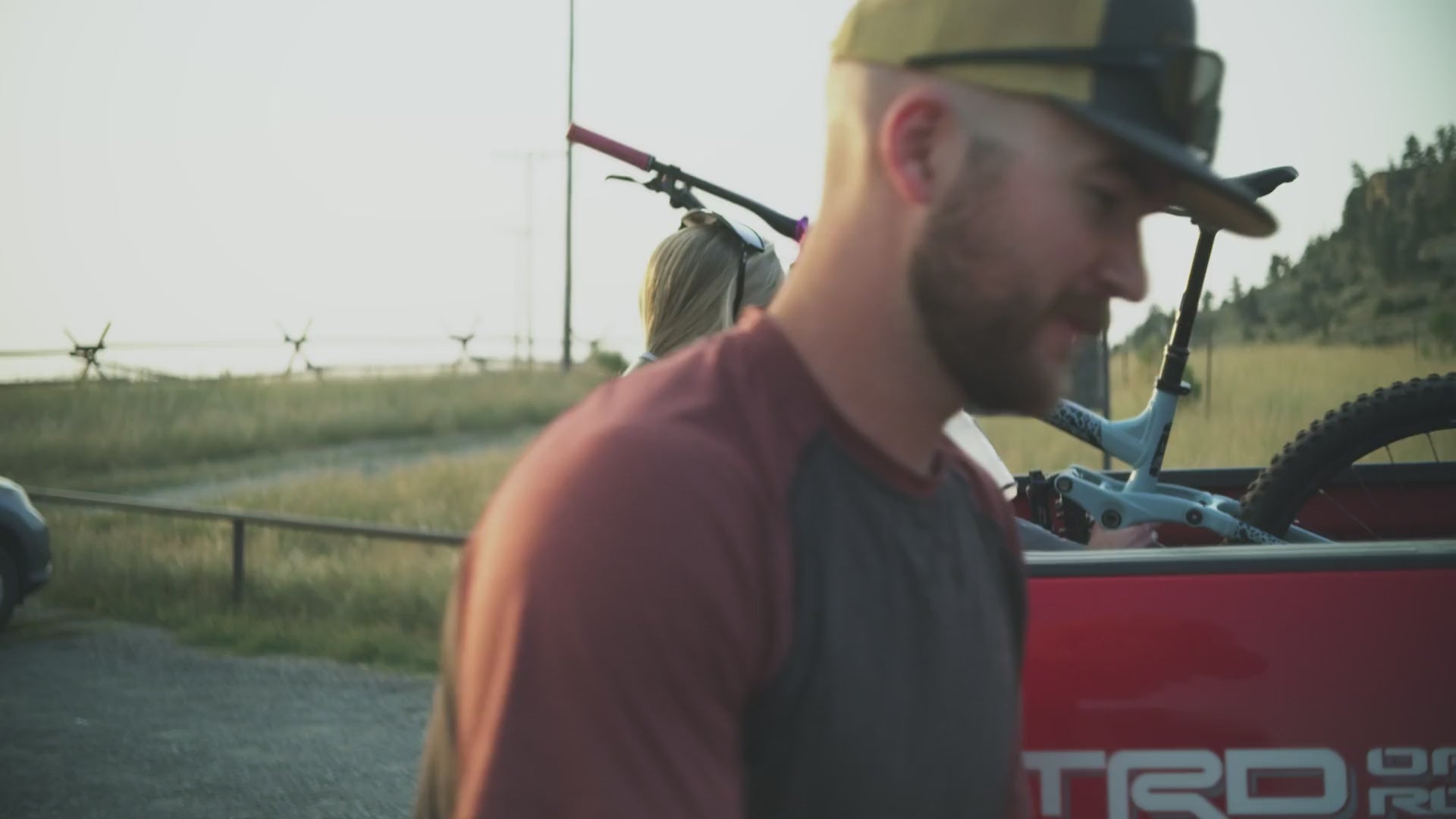 Load video: Cyclists unload their bikes from a truck, ready for an outdoor adventure.