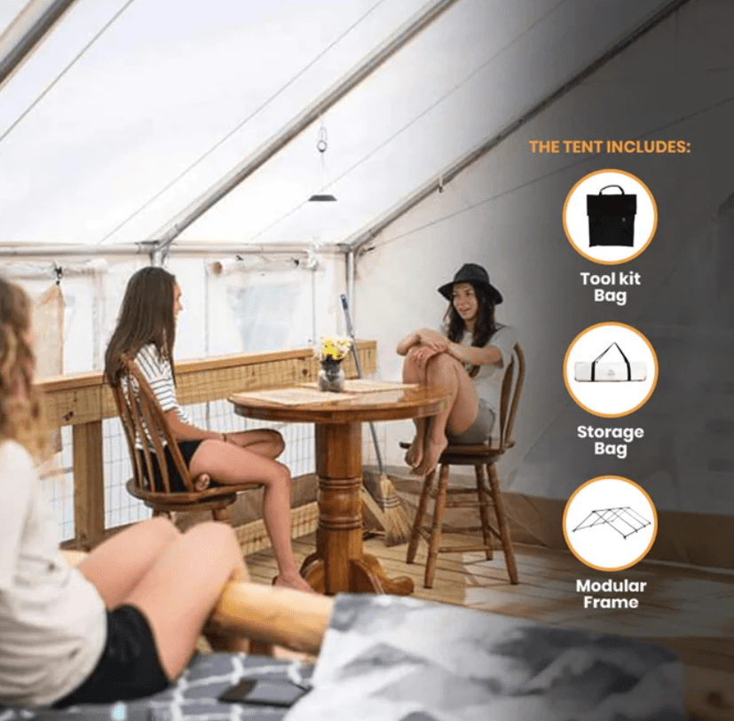 Two women sitting at a table in a tent, enjoying each other's company and engaging in conversation.